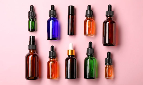 multi coloured glass bottles flatly on pink background.