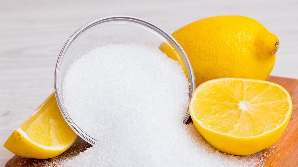 citric acid in bowl and lemons next to bowl.