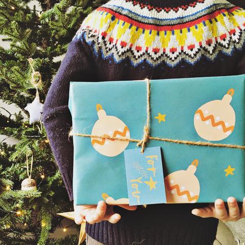 kid holding present in eco friendly blue big bauble wrapping paper.