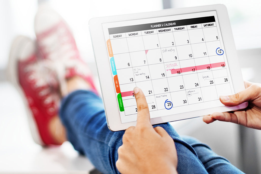 Persona relajada con los pies arriba planeando rutina en calendario de tableta