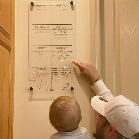 Dad showing child the family wall planner