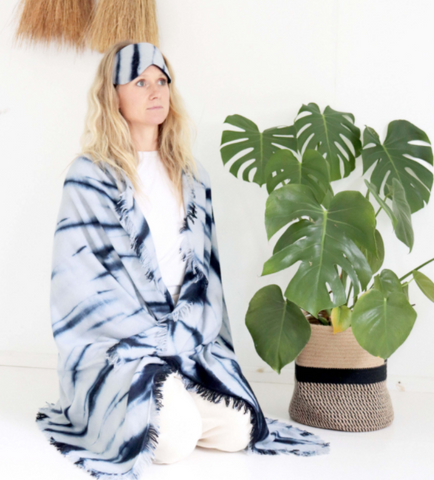 Woman wearing a Thread Tales eye mask and tie dye blanket