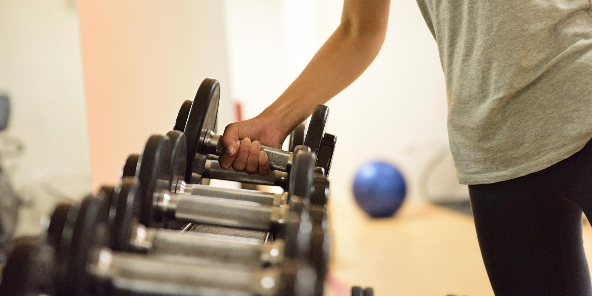 woman lifting weight off of the gym weight rack