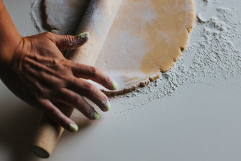 a woman baking with a wooden rolling pin