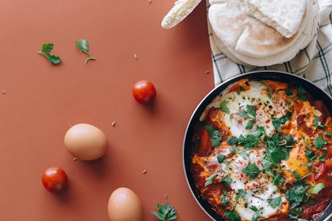 Eggs and Tomatoes on Red Surface with Shakshuka Pan