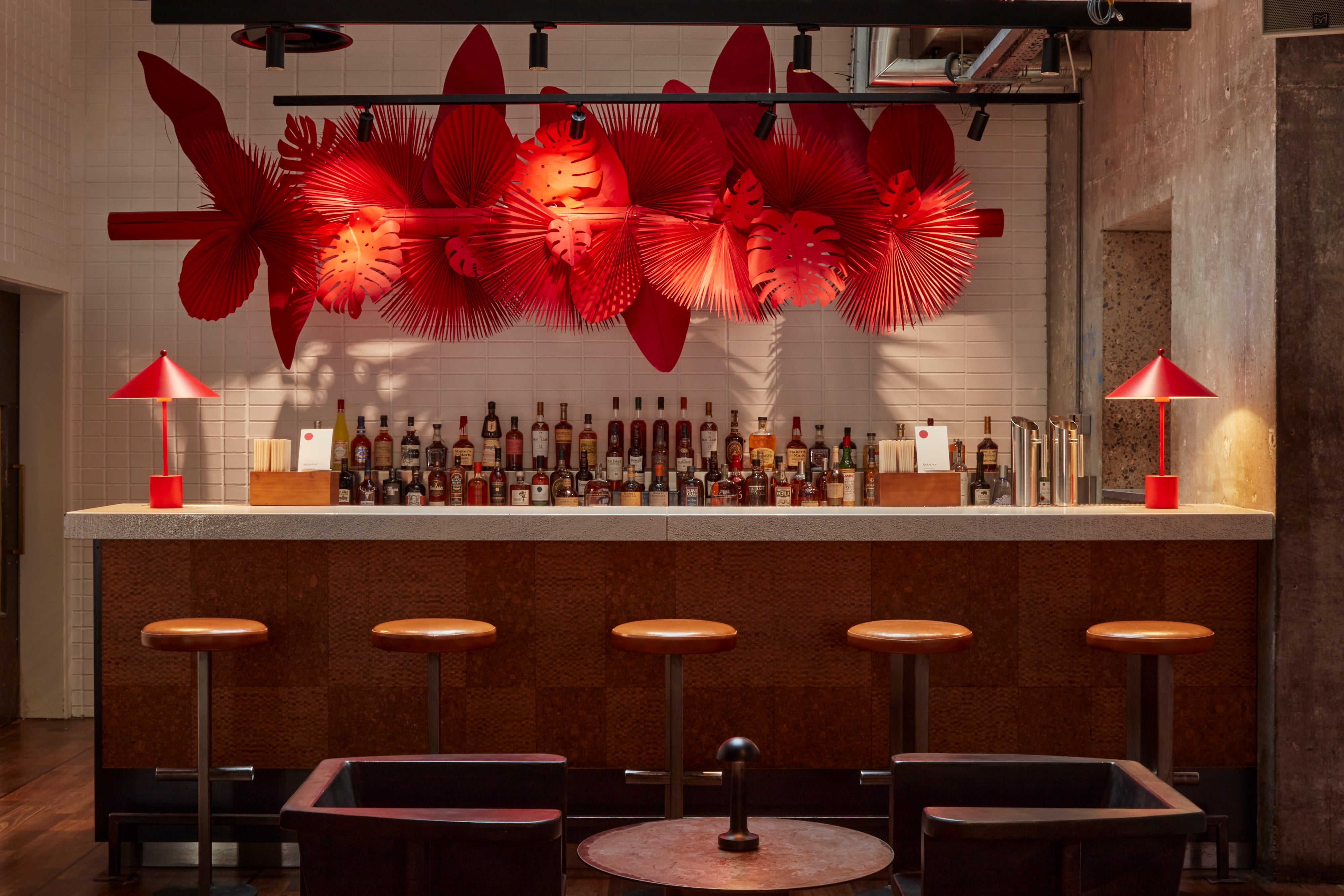 The vibrant red giant paper artwork adorning the Lobby Bar at One Hundred Shoreditch Hotel, creating an inviting and stylish atmosphere with its intricate design of tropical leaves.