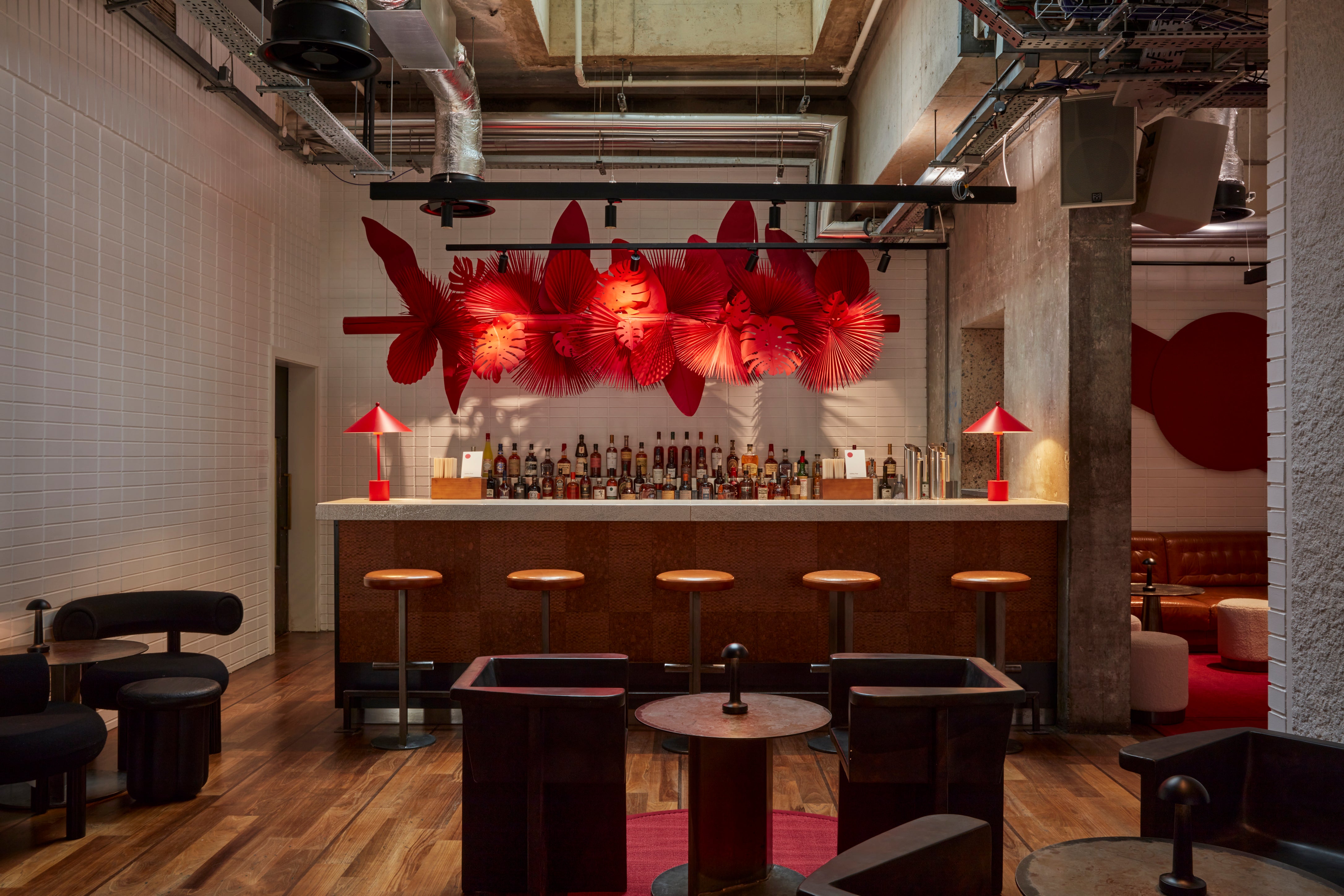 A captivating view of the transformed Lobby Bar at One Hundred Shoreditch Hotel, featuring a stunning giant paper artwork in vibrant red, showcasing the skillful arrangement of tropical leaves.