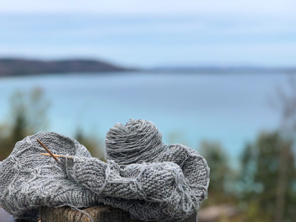 wool yarn WIP in front of a cool blue lake in michigan