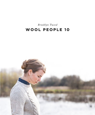 A woman on a lake shore models a hand knit cabled pullover. Title reads "Brooklyn Tweed Wool People 10"