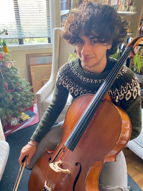 Emanuela's son sits near the Christmas tree in the family home, preparing to play his cello. 
