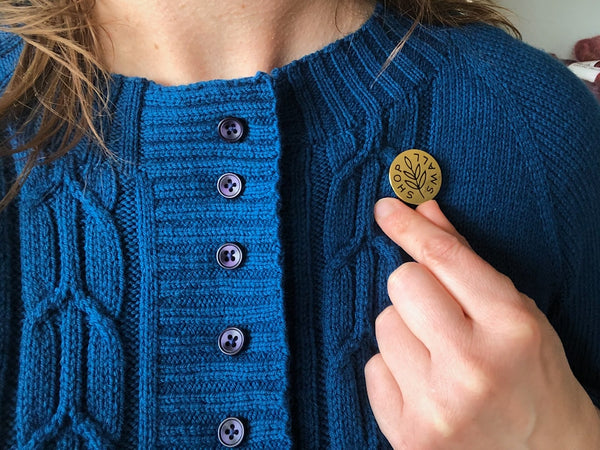 hand knit blue wool sweater sporting a button that reads Shop Small