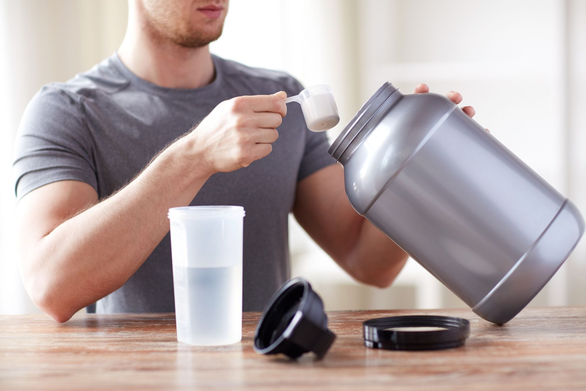 A muscular man scoops creatine into his shaker before going to the gym, but wonders whether creatine can cause acne.