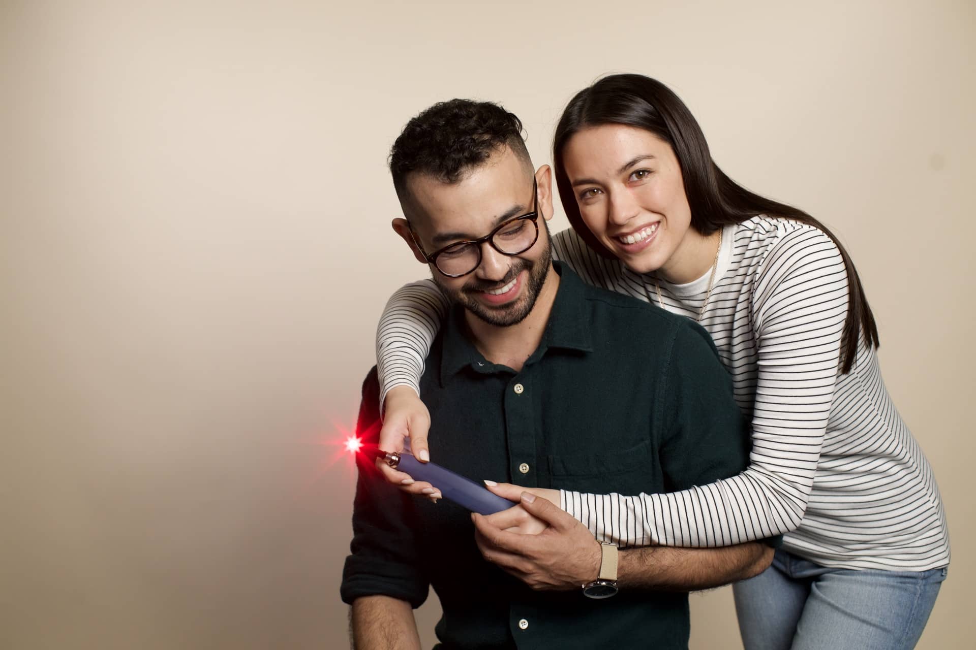 A man and woman hug while holding a light therapy device in an article on monolaurin for genital herpes.