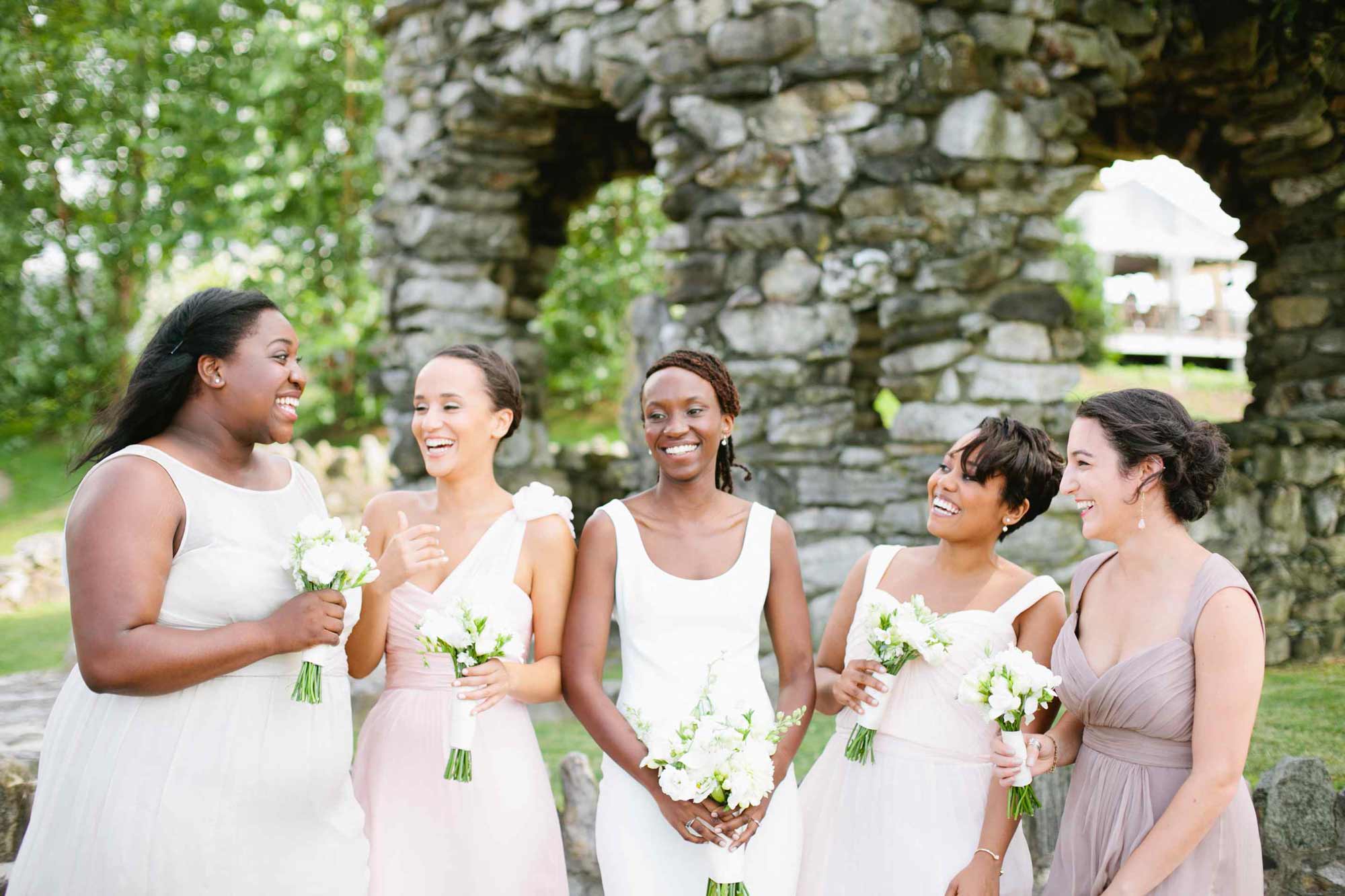 Group photo of 5 bridesmaids laughing at an outdoor wedding