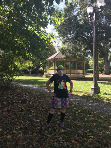 A runner stands in a park wearing a Nuu-Muu dress and a mask