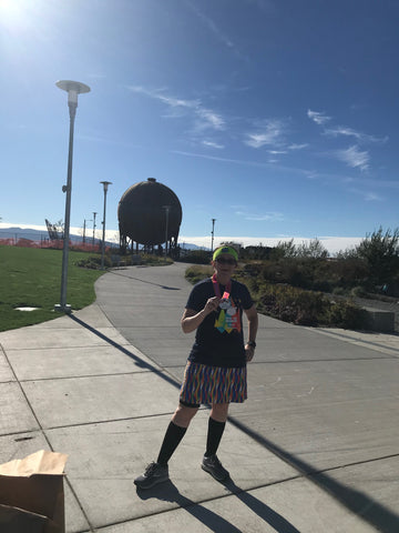 a runner standing in a park wearing a Nuu-Muu dress and holding a medal