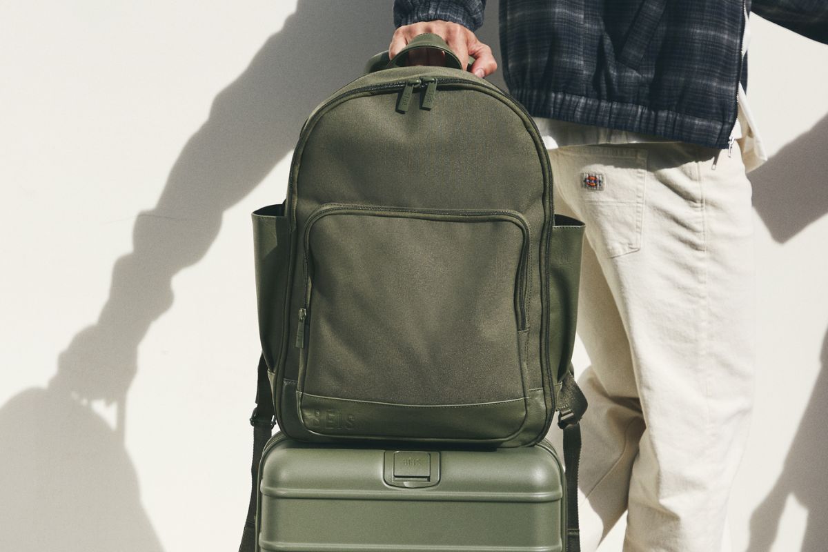 Green travel backpack on top of a green suitcase 