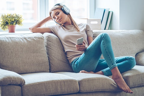 Resting with joy. Beautiful young woman listening to music and keeping eyes closed while sitting on sofa at home