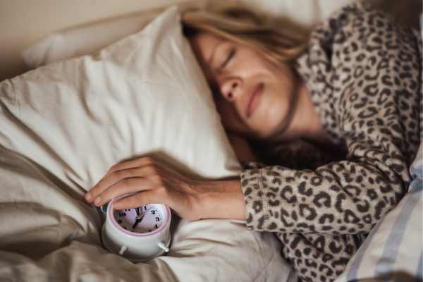 Woman avoiding her alarm clock and sleeping in late