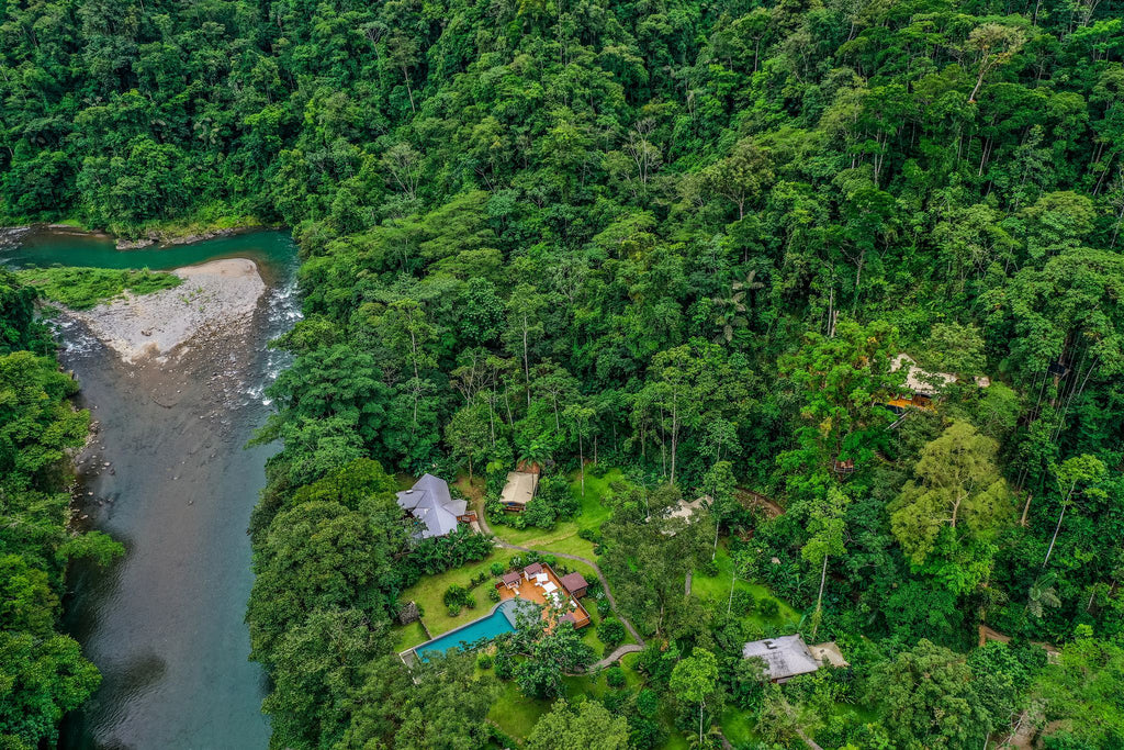 An aerial view of Pacuare Lodge in the Costa Rican rainforest. A river runs by the eco lodge.  