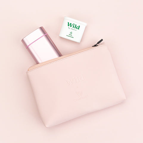 Birdseye image of the OneNine5 & Wild vegan leather, pink pouch.  zipped open with a wild deodorant & biodegradable refill poking out of the bag
