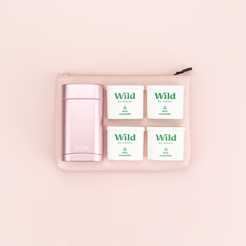 Birdseye view of the Wild deodorant case and four plastic-free, deodorant refills. Underneath the pink vegan leather pouch is visible.
