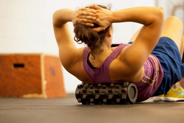 Woman on the floor using a foam roller on her back.