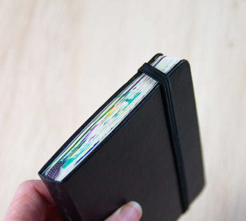 Image of the Moleskine Art Plus Pocket Size art sketchbook in hand showing the elastic closure