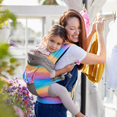 Mom hanging laundry with toddler on back in a carrier