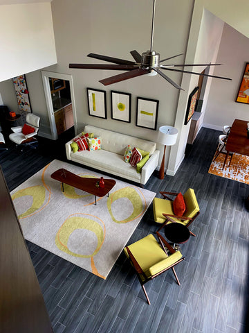 birds eye view of a living room with two handmade rugs. One rugs has yellow circle designs and the other is an orange geometric pattern both rugs designed by Christopher Fareed.