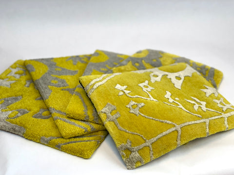 Five different rug samples with a floral design in yellow and gray. Each sample is made with different weaving techniques and materials.