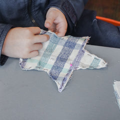 A childs hand sewing a star