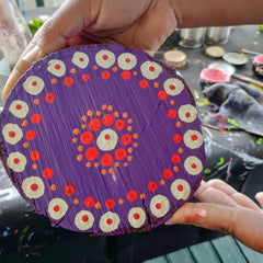 A wooden disk painted with dot art