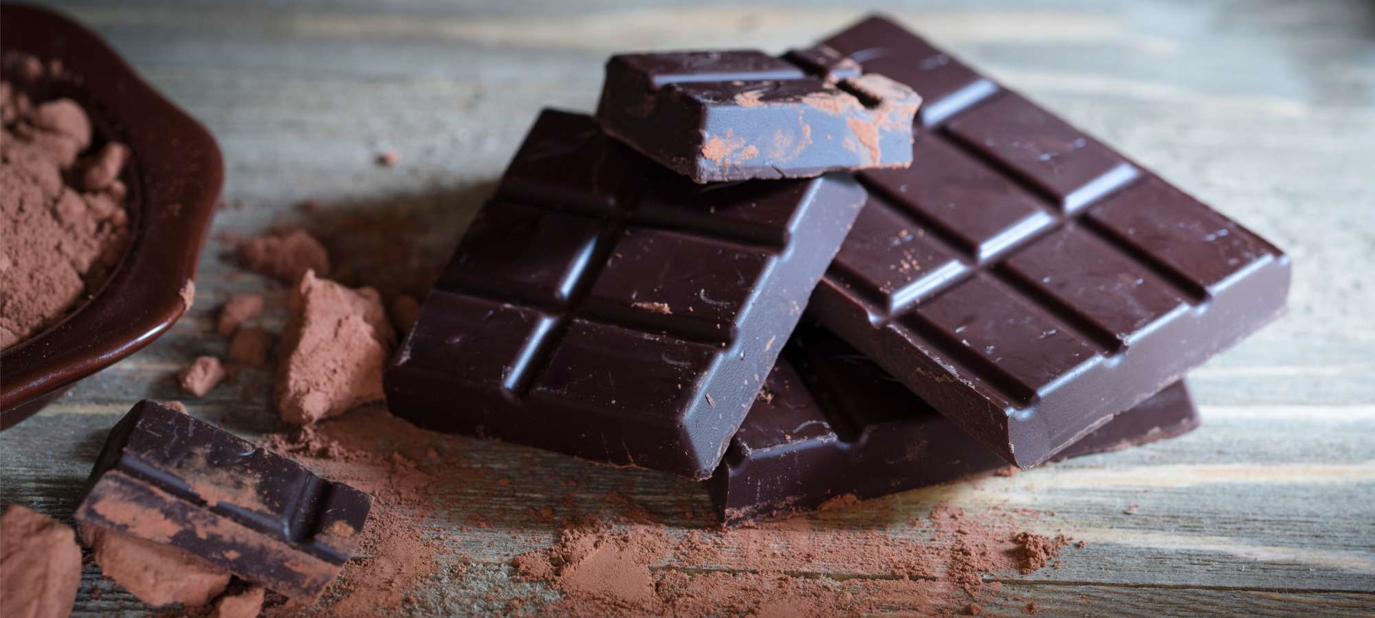 dark chocolate on white table with cocoa powder