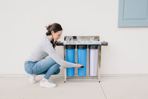a woman crouched while installing the NU Aqua whole house filtration system