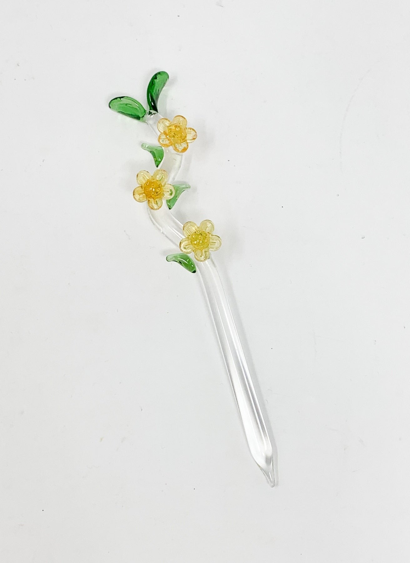 A delicate glass floral dab tool with green leaf and yellow flower adornments