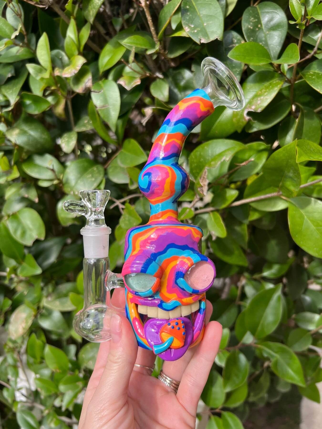 a rainbow, trippy skeleton face glass pipe