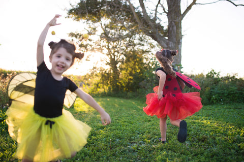 Kids dressed up as a bee and ladybug playing outside.