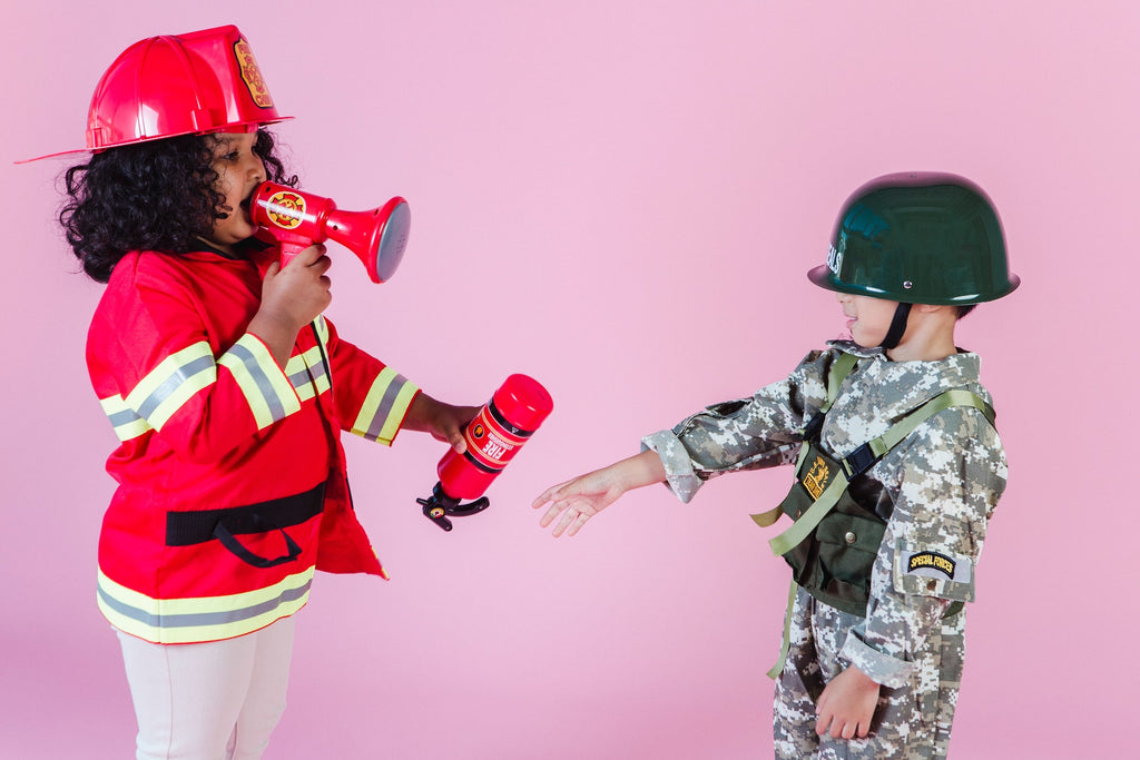 A girl in a fireman costume and a boy in a soldier costume talking to each other.