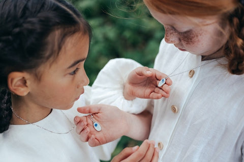 Two girls playing with their necklaces as an example of how children's jewelry adds magic to their world