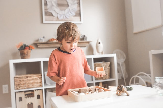 Boy in an orange sweater playing in his room.