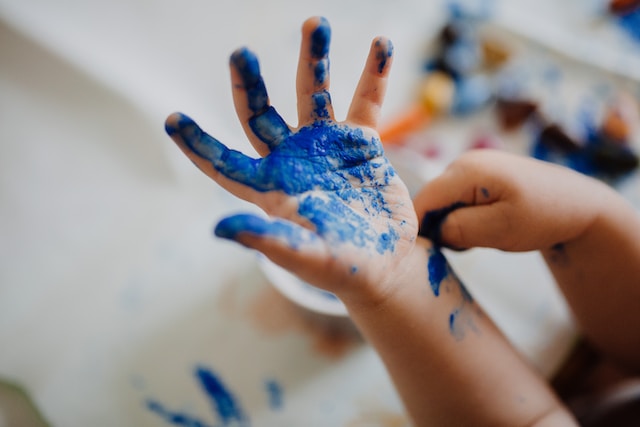 Child's hand dipped into the blue paint.