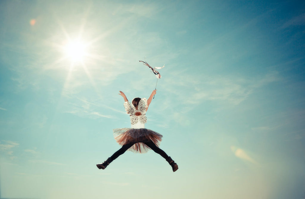 A girl with butterfly wings jumping high in the sky.