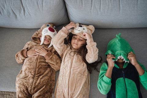 Three kids in animal costumes lying on a sofa.