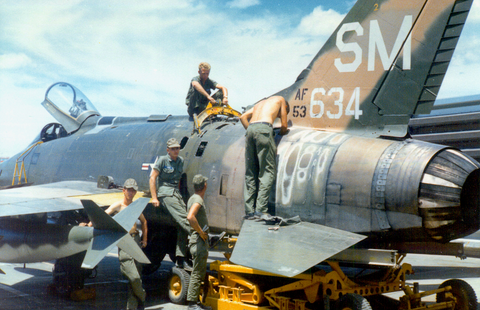 Aircraft mechanics wearing OD green fatigues and working on an F-100 Super Sabre aircraft