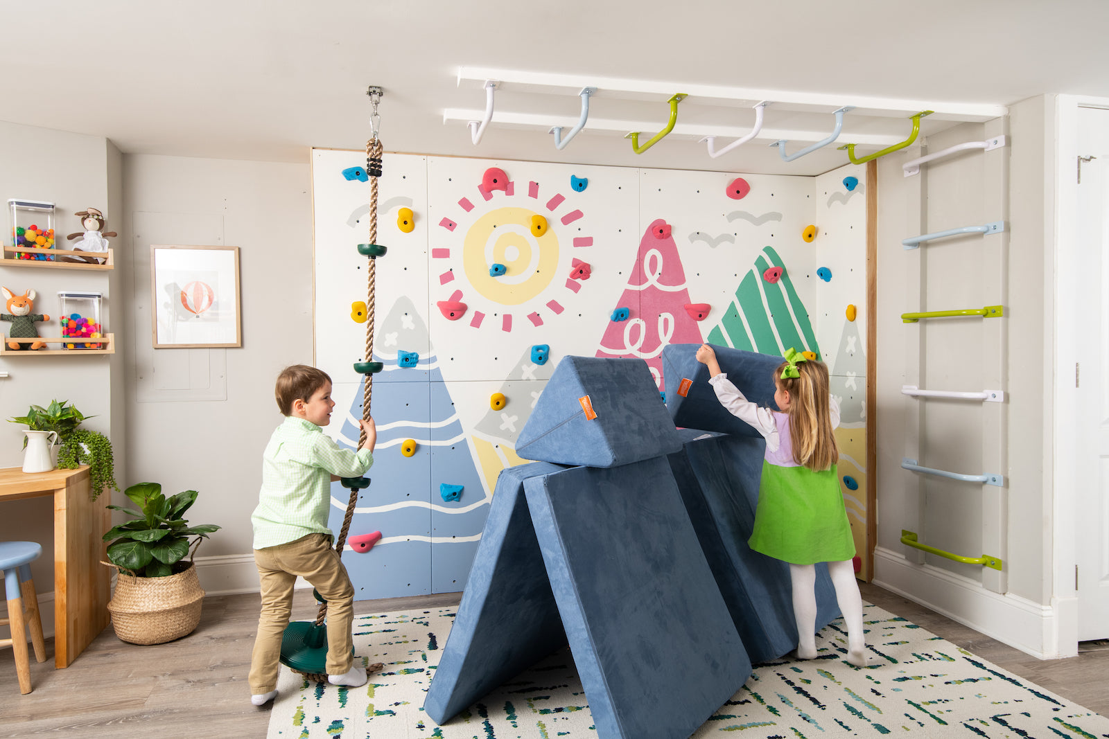 One child pulls on a climbing rope while another adjusts a Nugget Pillow on a Nugget tunnel