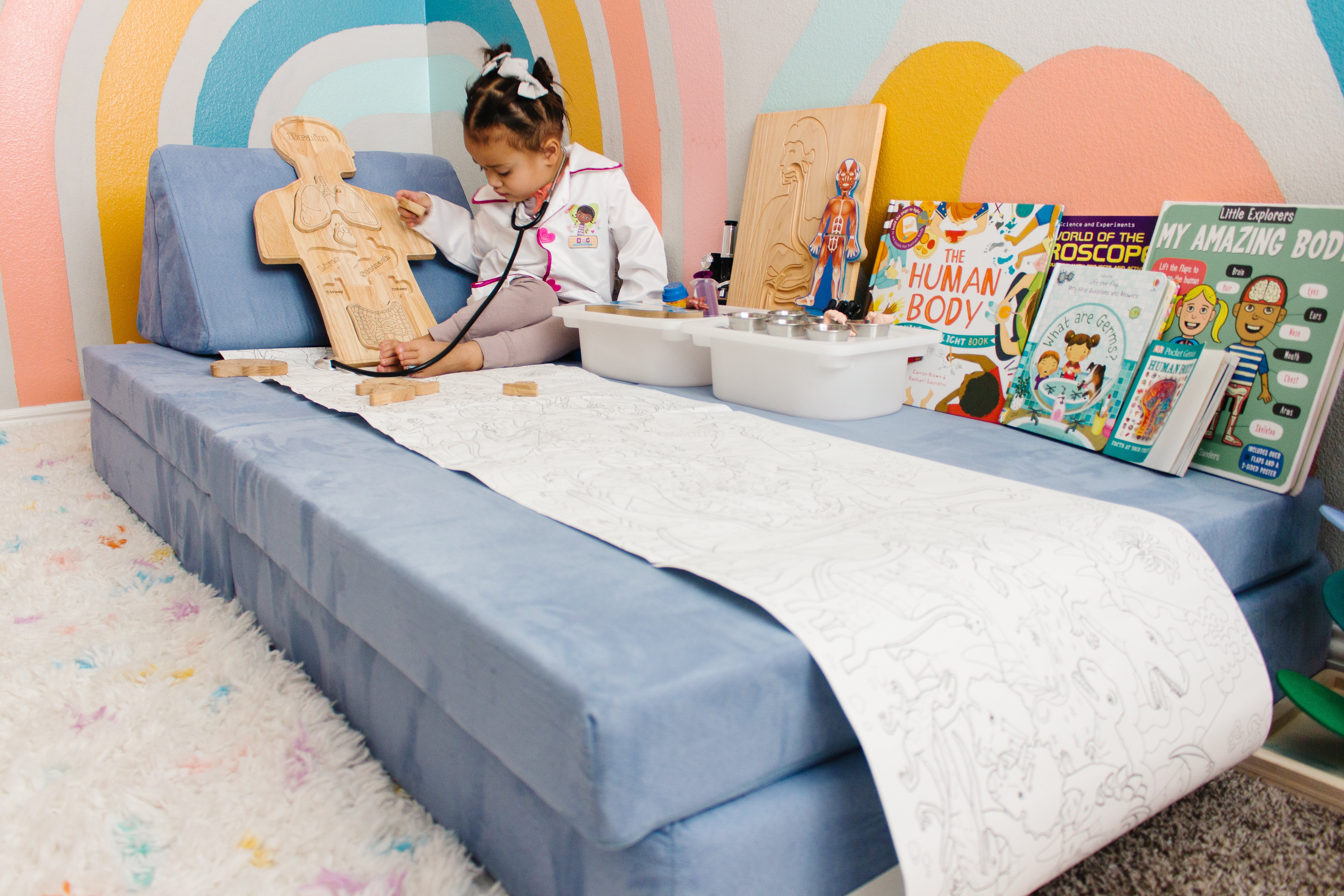 Kid dressed up as doctor, playing with their stethoscope on a Nugget set up as a patient room