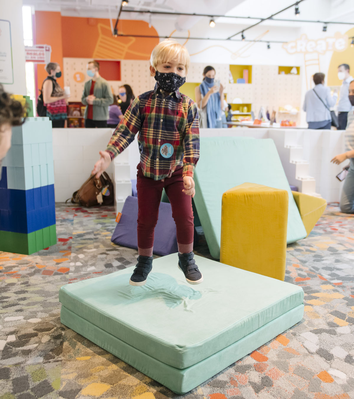 Child jumping on Nugget cushion at ImagiFAB exhibit opening