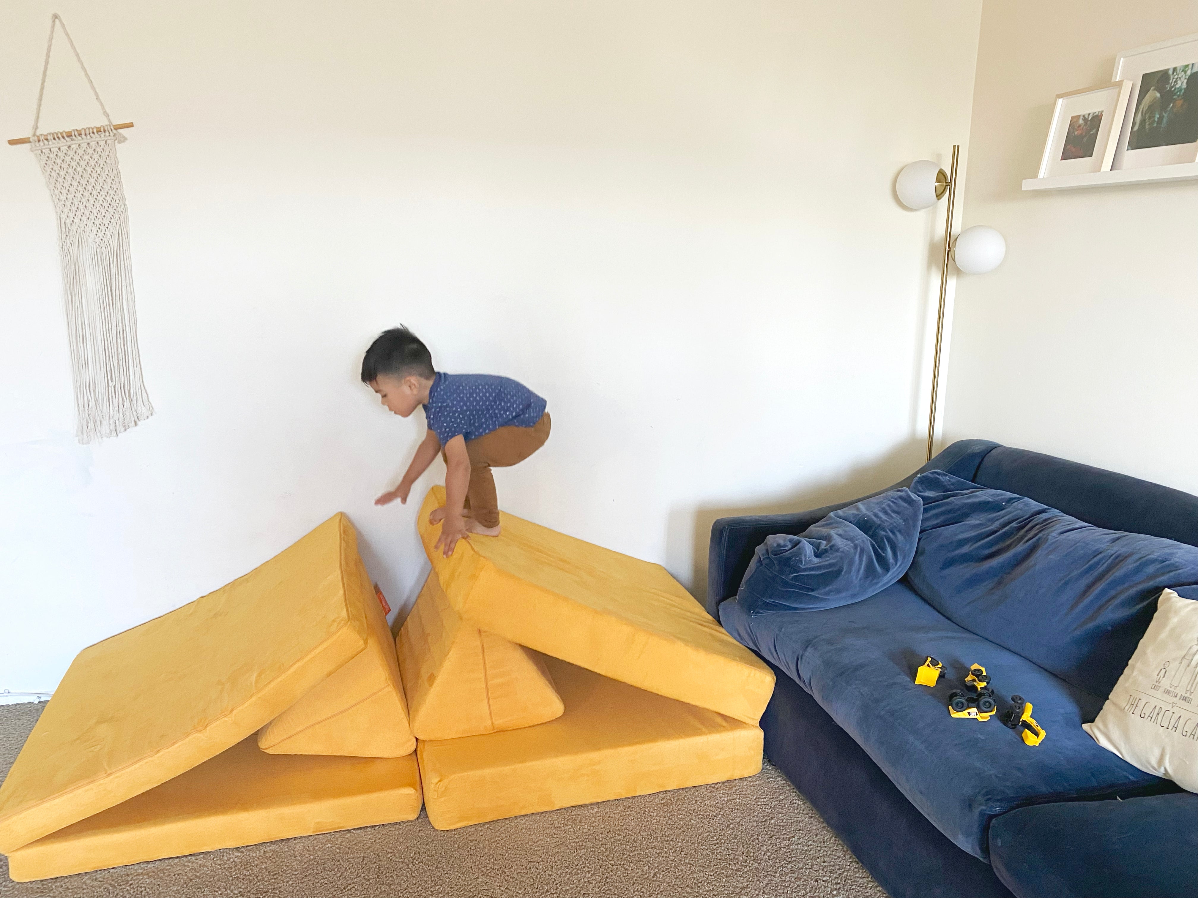 Child crouching in preparation of jumping between two cushion/pillow ramps