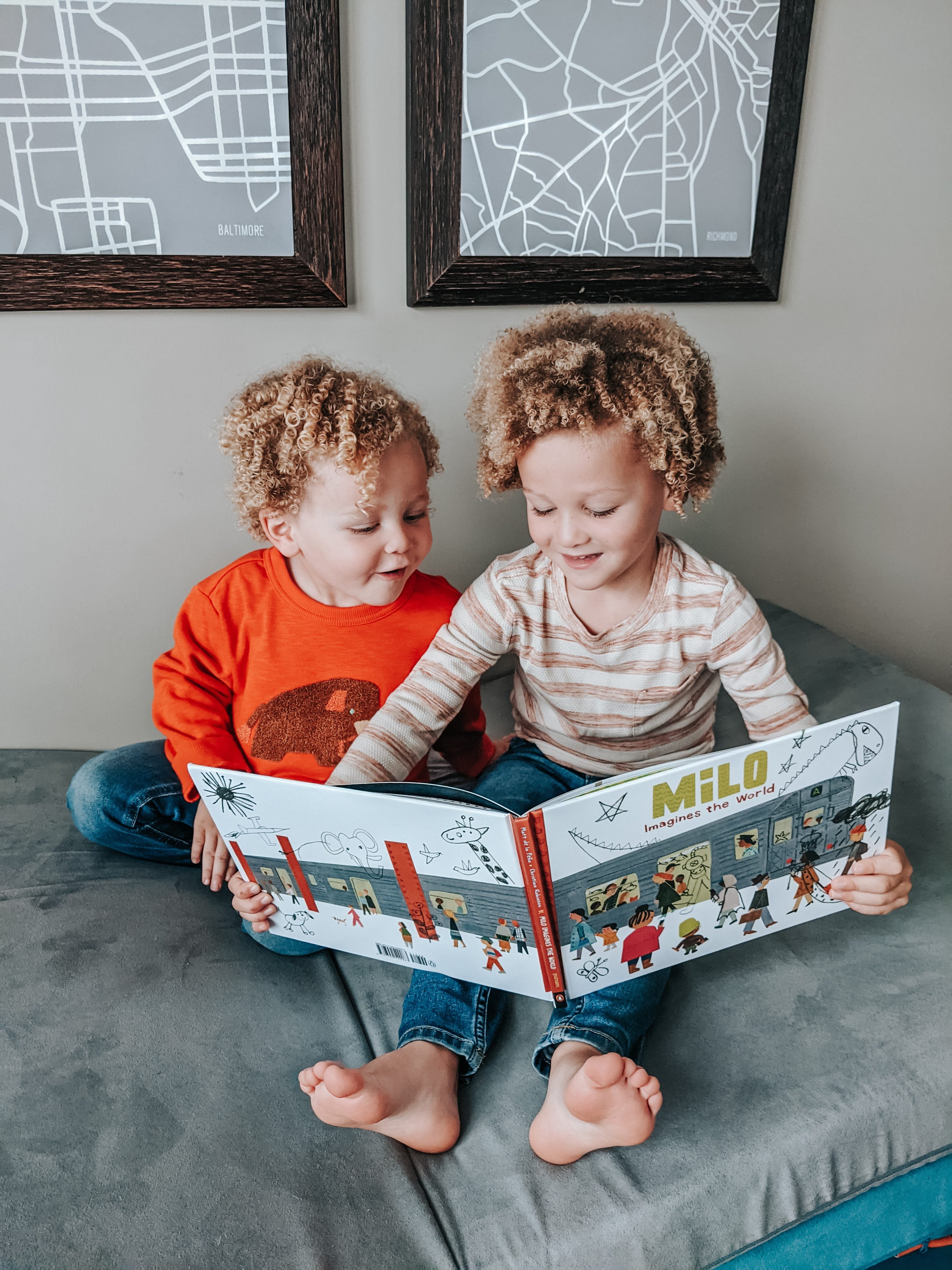 Two curly-headed children holding open "Milo" book, Big Curly holding the book while Little Curly looks at the images